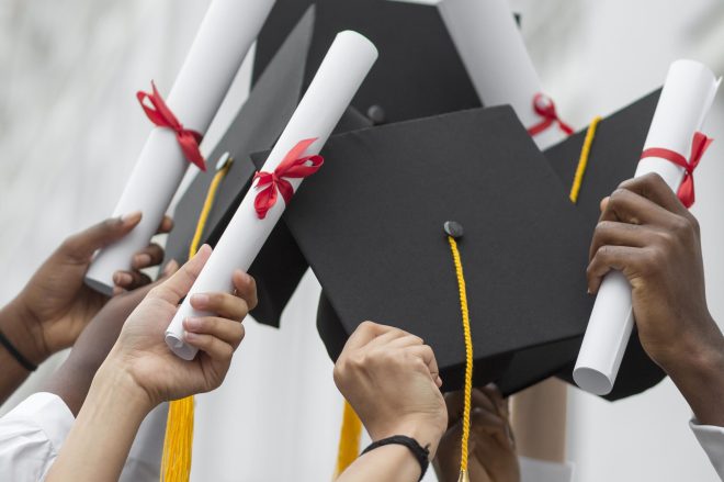 close-up-hands-holding-diplomas-caps